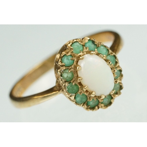 136 - Emerald and opal 9ct yellow gold cluster ring, the oval precious white opal displaying orange and re... 