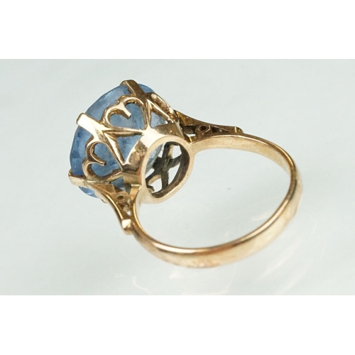 139 - Blue stone rose metal ring, the blue stone possibly paste or synthetic spinel, claw set, ring size O... 