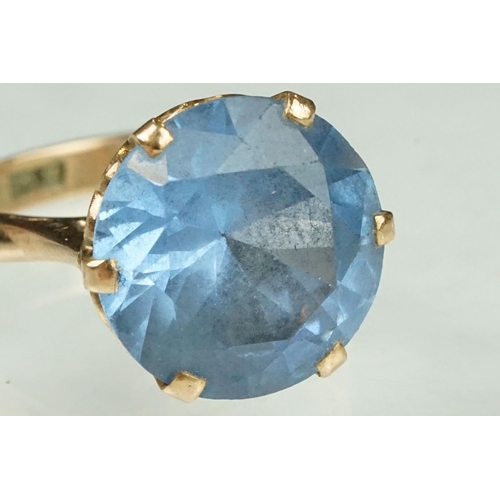 139 - Blue stone rose metal ring, the blue stone possibly paste or synthetic spinel, claw set, ring size O... 