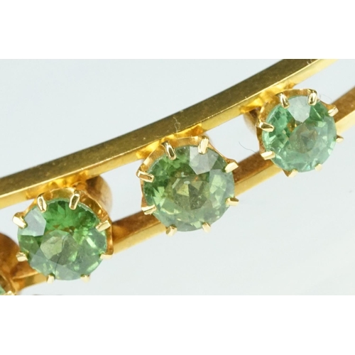 5 - Late 19th century green stone 18ct yellow gold hinged bangle, nine round cut green stones, possibly ... 