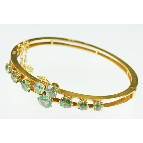 5 - Late 19th century green stone 18ct yellow gold hinged bangle, nine round cut green stones, possibly ... 