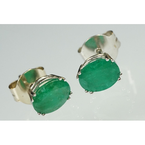 94 - Pair of emerald white metal stud earrings, the oval mixed cut emerald measuring approx 10mm x 8mm, c... 