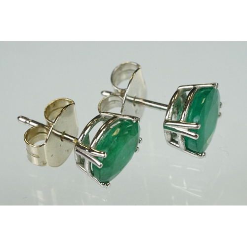 94 - Pair of emerald white metal stud earrings, the oval mixed cut emerald measuring approx 10mm x 8mm, c... 