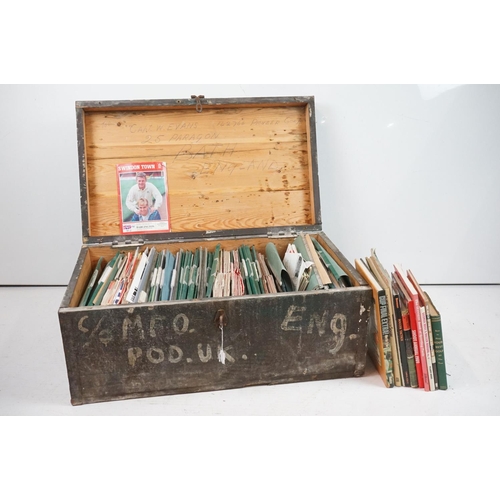 196 - A large collection of Swindon Town football club programmes contained within a large wooden storage ... 