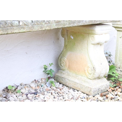273 - Reconstituted stone garden bench / seat of rectangular form, raised on two feet scrolled feet. (Meas... 