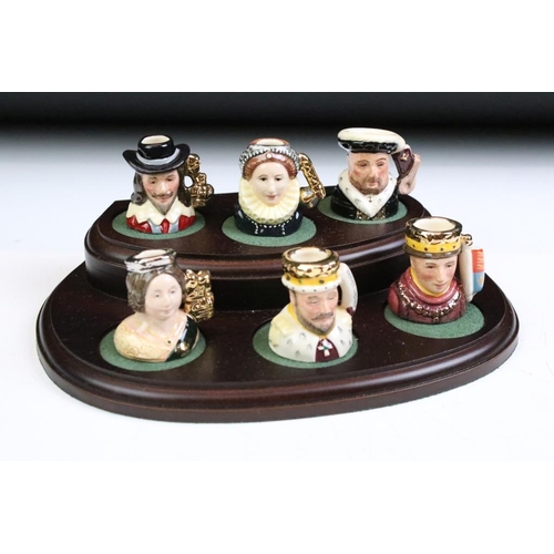 97 - Set of Six Royal Doulton 'Kings & Queens of the Realm' tiny character jugs on wooden display stand (... 