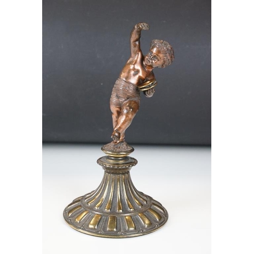 189 - Antique cast bronze putti figurine depicting a classical putti with symbols raised on a fluted cast ... 