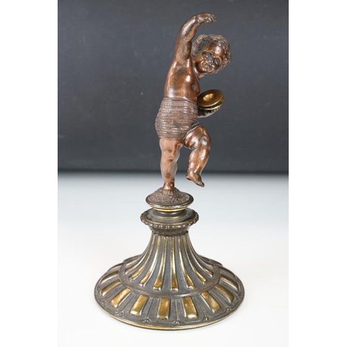 189 - Antique cast bronze putti figurine depicting a classical putti with symbols raised on a fluted cast ... 