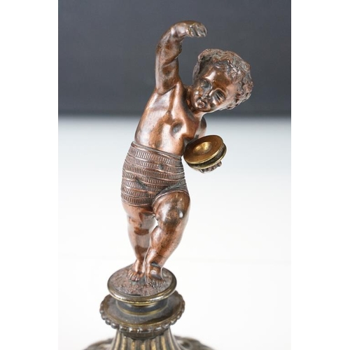 189 - Antique cast bronze putti figurine depicting a classical putti with symbols raised on a fluted cast ... 