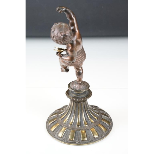 189 - Antique cast bronze putti figurine depicting a classical putti with symbols raised on a fluted cast ... 