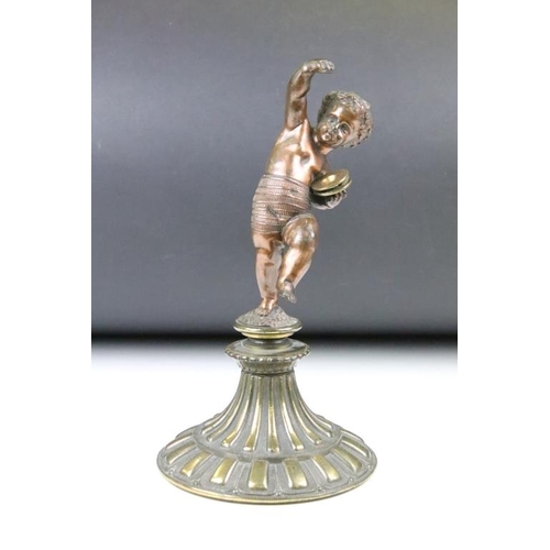 189 - Antique cast bronze putti figurine depicting a classical putti with symbols raised on a fluted cast ... 