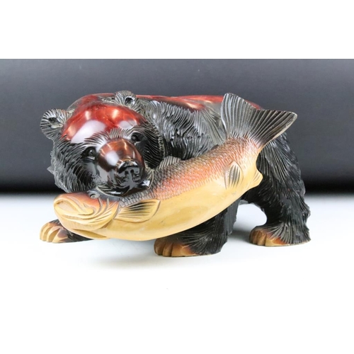 192 - Carved North American style wooden figure in the form of a bear catching salmon. Measures 16cm.