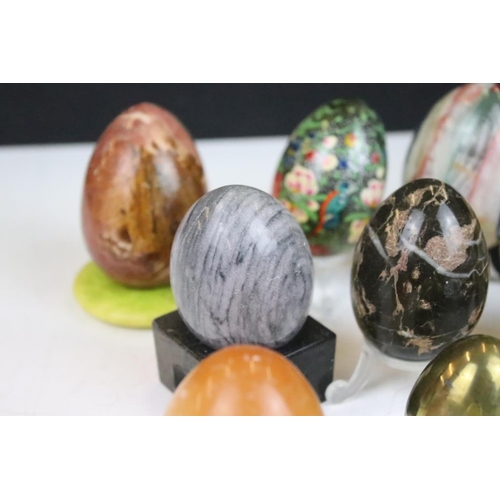 370 - A collection of decorative ornamental eggs to include polished stone and lacquer ware examples.