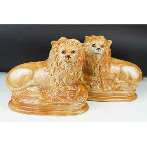 102 - Pair of Victorian Staffordshire pottery recumbent lion mantel figures with glass eyes, approx 24cm h... 