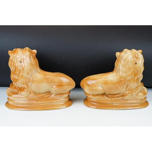 102 - Pair of Victorian Staffordshire pottery recumbent lion mantel figures with glass eyes, approx 24cm h... 