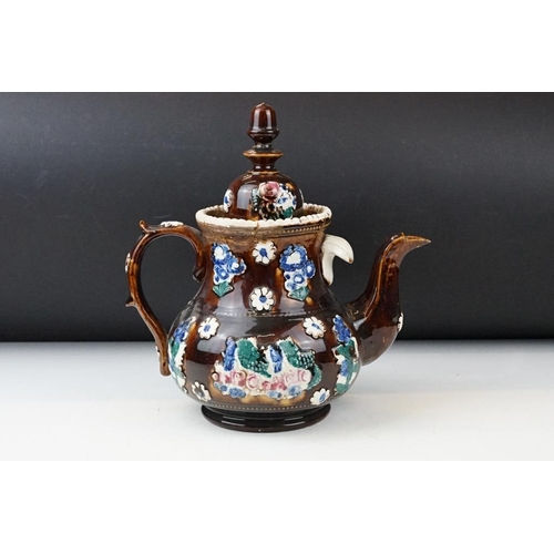 104 - 19th Century Measham pottery bargeware teapot & cover, having typical moulded floral motifs on a bro... 