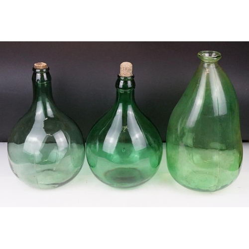 37 - Three green glass bottles / carboys to include a pair of bulbous form (with stoppers) and a further ... 