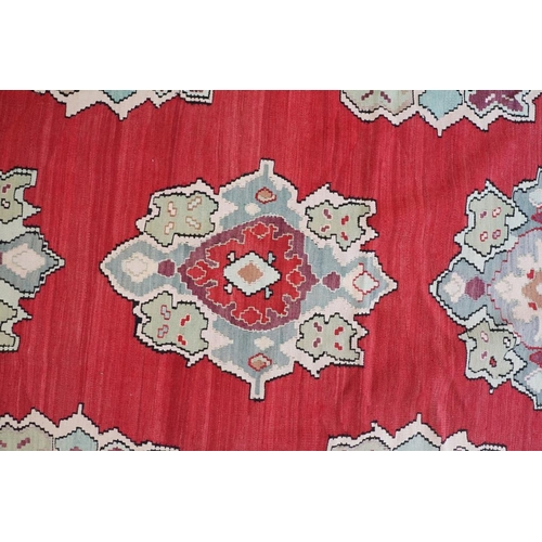 597 - Kilim Gocmen Rug, the red ground decorated with medallions within a black border, 331cm x 224cm