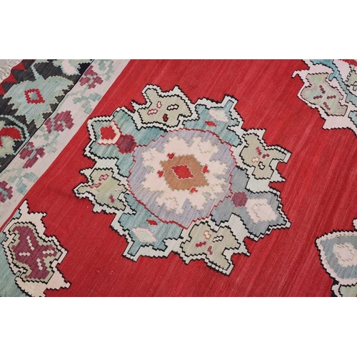 597 - Kilim Gocmen Rug, the red ground decorated with medallions within a black border, 331cm x 224cm