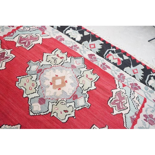 597 - Kilim Gocmen Rug, the red ground decorated with medallions within a black border, 331cm x 224cm