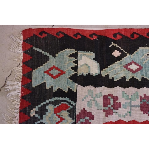 597 - Kilim Gocmen Rug, the red ground decorated with medallions within a black border, 331cm x 224cm