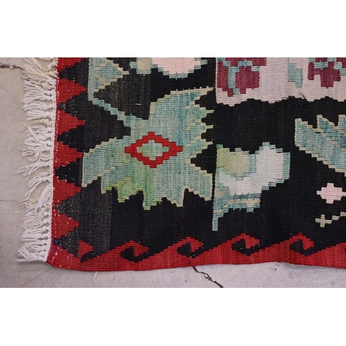 597 - Kilim Gocmen Rug, the red ground decorated with medallions within a black border, 331cm x 224cm