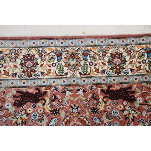 636 - Persian style Rug, the pink ground with a pattern of stylised hunting big cats and deer with birds a... 