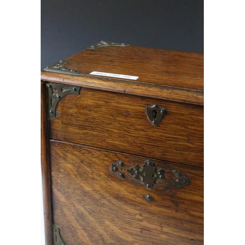 160 - Edwardian oak stationery cabinet, the raising of the lid causing the lower compartment to open, the ... 