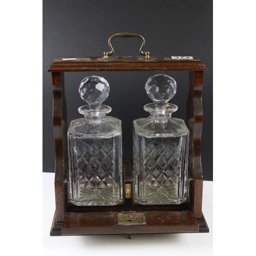 174 - Early 20th century mahogany tantalus with brass mounts, housing a pair of glass decanters & stoppers... 