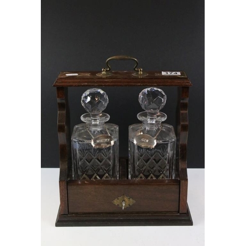 174 - Early 20th century mahogany tantalus with brass mounts, housing a pair of glass decanters & stoppers... 