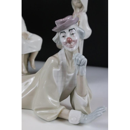 58 - Four Lladro figurines to include a large recumbent clown figure, yawning boy, reading boy and hooded... 