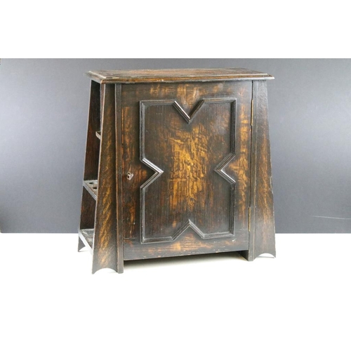 190 - Early-to-mid 20th century oak smokers cabinet of tapering form, the door opening to two drawers and ... 