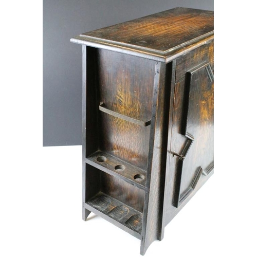 190 - Early-to-mid 20th century oak smokers cabinet of tapering form, the door opening to two drawers and ... 