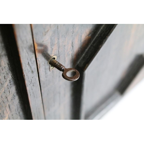 190 - Early-to-mid 20th century oak smokers cabinet of tapering form, the door opening to two drawers and ... 