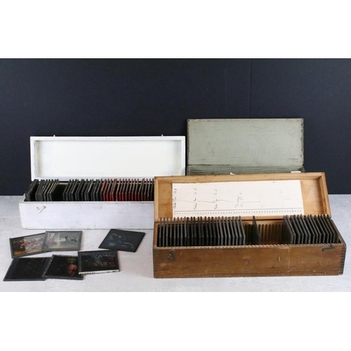 623 - A collection of approx 100 x glass magic lantern slides contained within three wooden cases to inclu... 