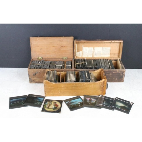 625 - A collection of approx 100 x glass magic lantern slides contained within three wooden cases to inclu... 