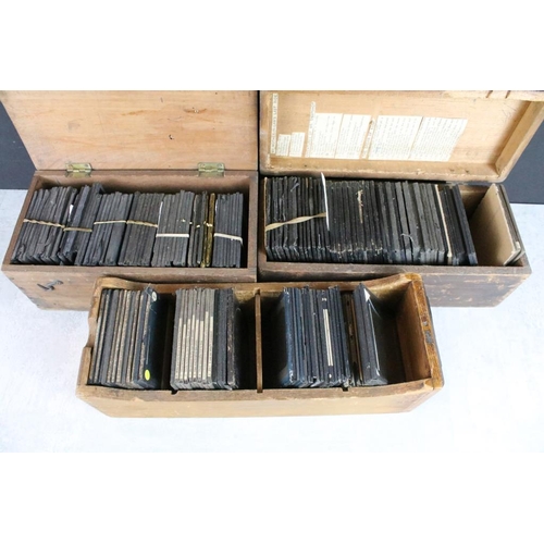 625 - A collection of approx 100 x glass magic lantern slides contained within three wooden cases to inclu... 