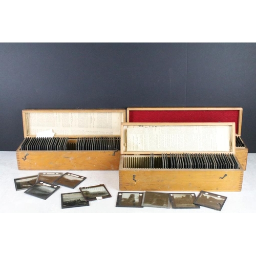 627 - A collection of over 100 glass magic lantern slides contained within three wooden cases to include t... 