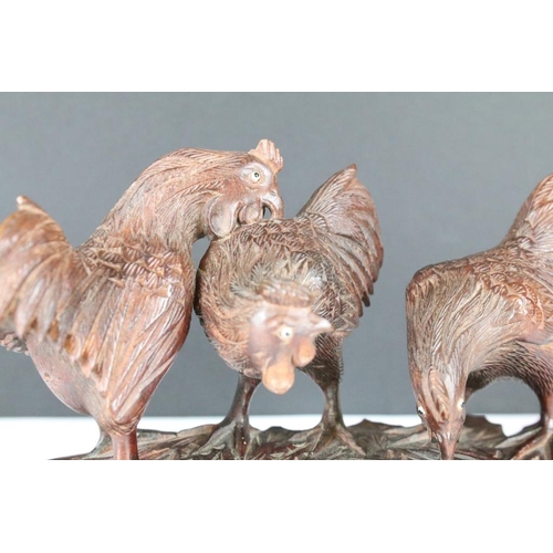 206 - A hand carved wooden oriental ornament of three chickens / cocks on raised base, approx 15cm wide