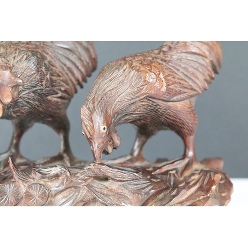 206 - A hand carved wooden oriental ornament of three chickens / cocks on raised base, approx 15cm wide