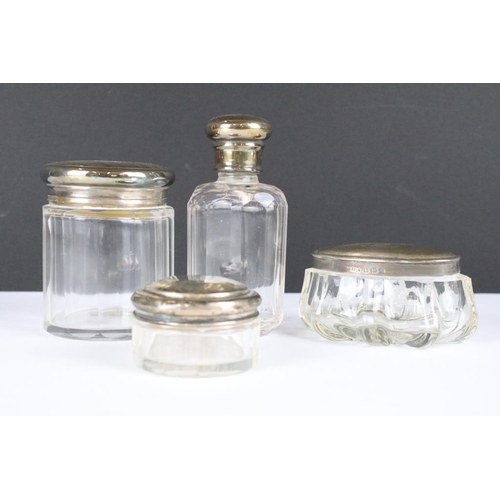 256 - A collection of antique glass jars and scent bottles with hallmarked silver tops and collars.