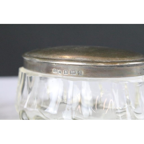 256 - A collection of antique glass jars and scent bottles with hallmarked silver tops and collars.