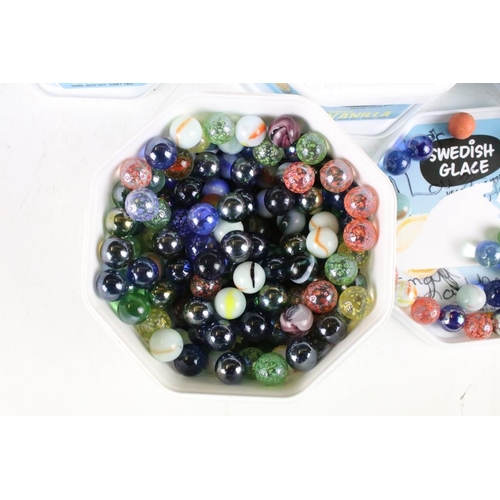 303 - A large collection of mixed glass marbles contained within six boxes.