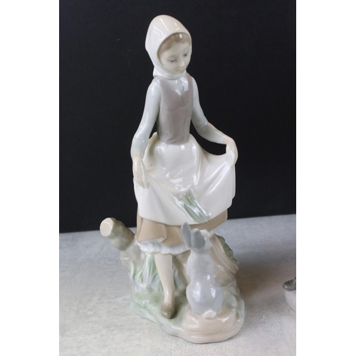 47 - Three Lladro figurines to include a boy holding a model ship, lady with a hare and a girl with a kit... 