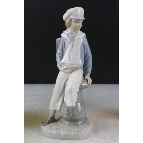 47 - Three Lladro figurines to include a boy holding a model ship, lady with a hare and a girl with a kit... 