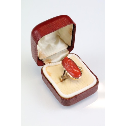 32 - 19th century coral 9ct gold ring, the carved coral modelled as a female head with hat, rubover set, ... 