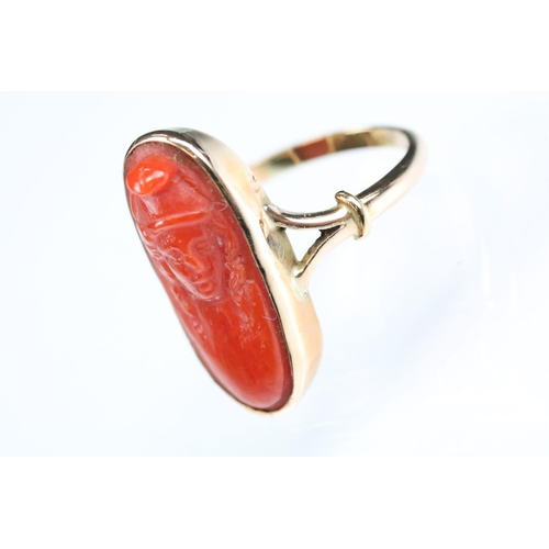 32 - 19th century coral 9ct gold ring, the carved coral modelled as a female head with hat, rubover set, ... 