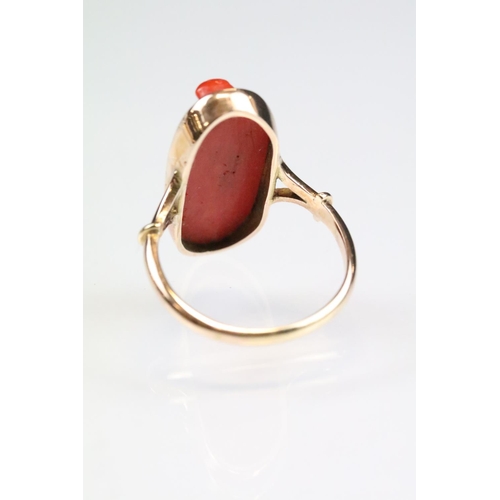 32 - 19th century coral 9ct gold ring, the carved coral modelled as a female head with hat, rubover set, ... 