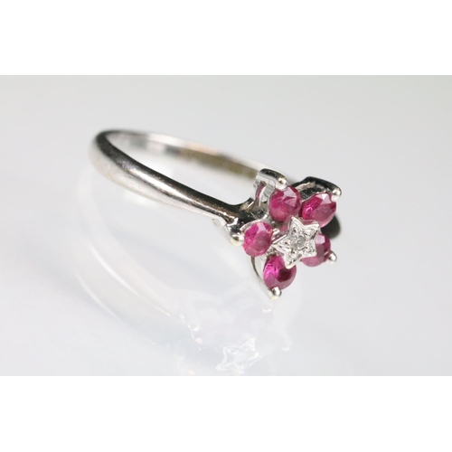 91 - Ruby and diamond 9ct white gold flower head ring, central small round eight cut diamond to centre, i... 