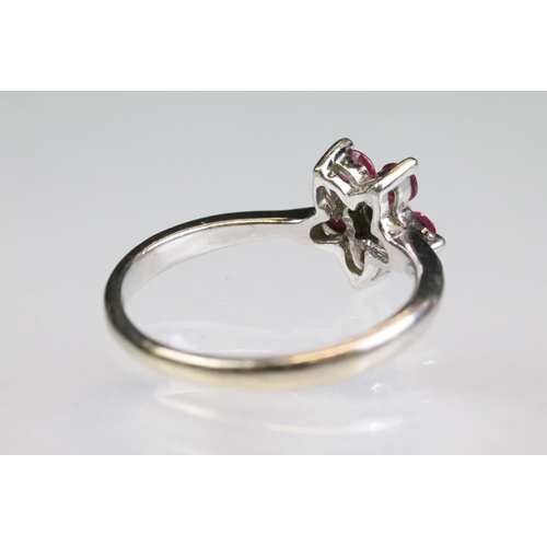 91 - Ruby and diamond 9ct white gold flower head ring, central small round eight cut diamond to centre, i... 